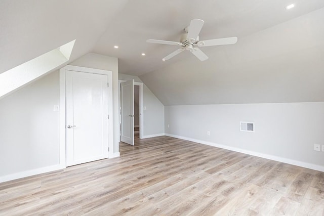 bonus room featuring baseboards, lofted ceiling with skylight, ceiling fan, visible vents, and light wood-type flooring