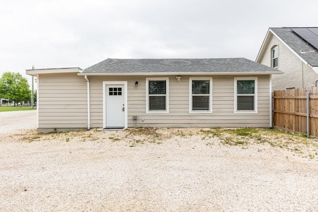 back of house featuring roof with shingles and fence