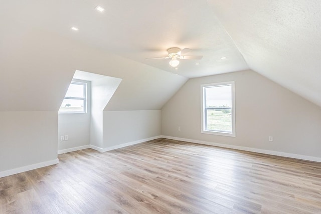 bonus room with baseboards, light wood-style flooring, lofted ceiling, and ceiling fan