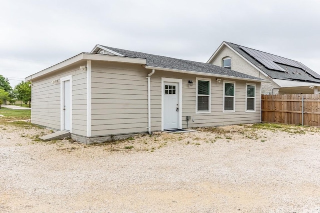 rear view of house with roof with shingles and fence