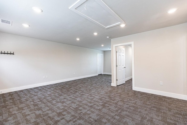 empty room featuring dark colored carpet, attic access, visible vents, and recessed lighting