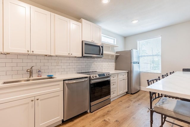 kitchen with white cabinetry, light countertops, stainless steel appliances, and a sink
