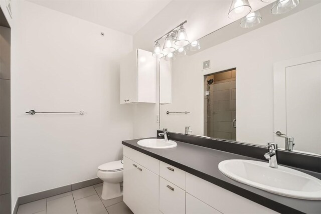 4361 S Congress Ave Unit 236, Austin, TX 78745 - full bathroom featuring toilet, double vanity, a tile shower, tile patterned floors, and baseboards