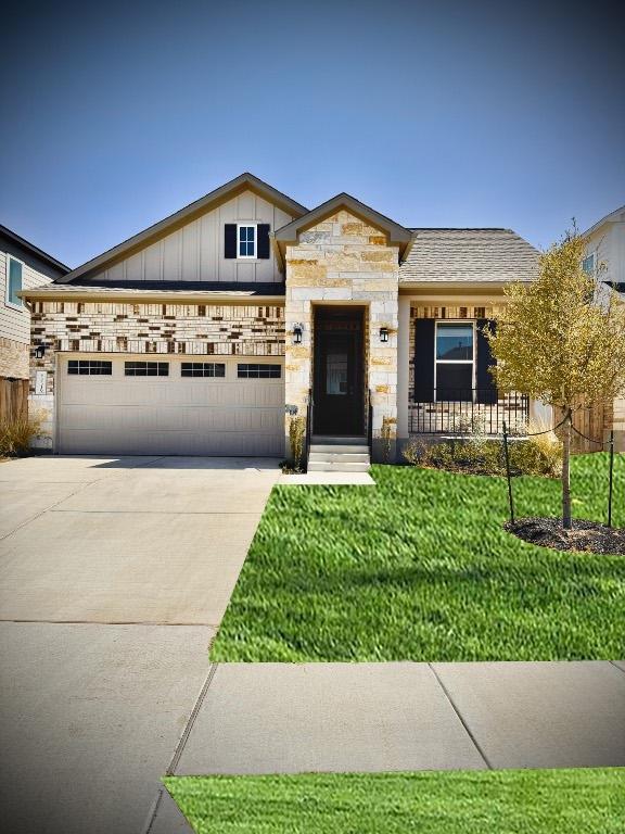 4319 Port Hope St, Round Rock, TX 78665 - view of front of house featuring a garage, stone siding, driveway, a front yard, and board and batten siding