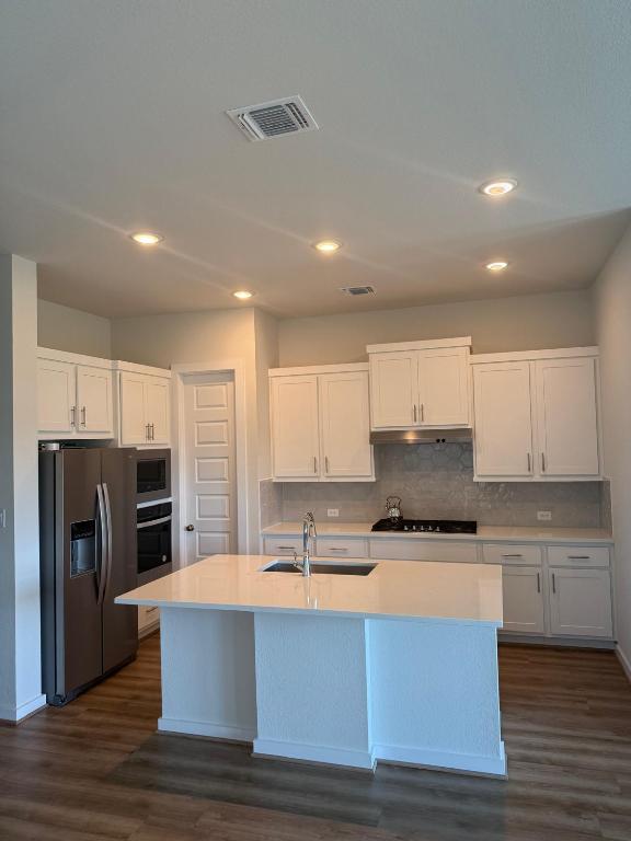 4319 Port Hope St, Round Rock, TX 78665 - kitchen with stainless steel appliances, white cabinets, dark wood finished floors, light countertops, and under cabinet range hood