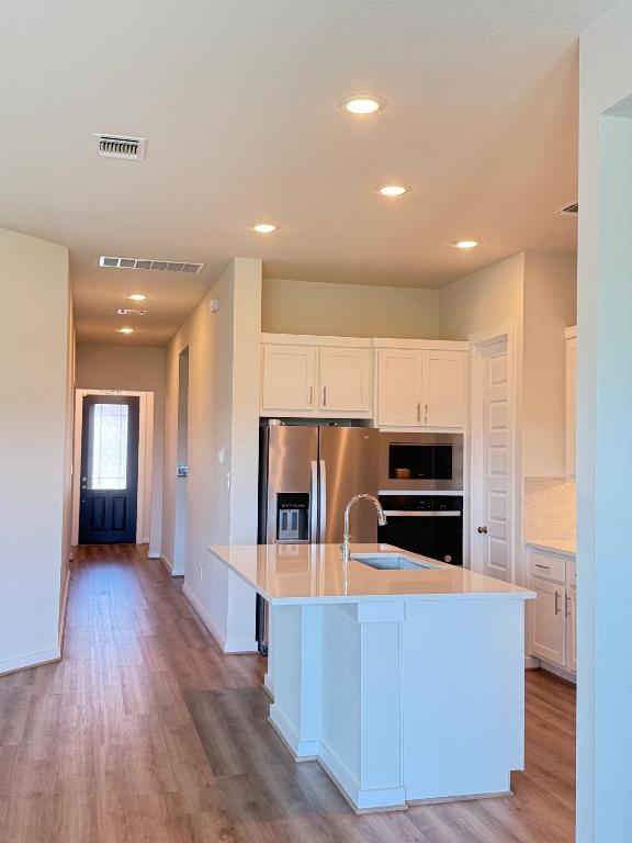 4319 Port Hope St, Round Rock, TX 78665 - kitchen featuring appliances with stainless steel finishes, light wood-type flooring, white cabinets, and recessed lighting