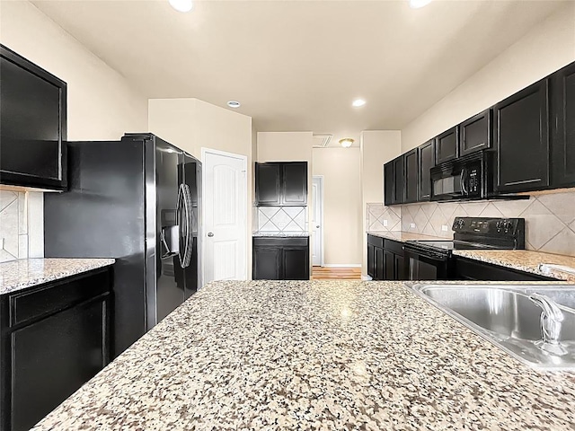 127 Navidad River Dr, Hutto, TX 78634 - kitchen with black appliances, dark cabinetry, a sink, decorative backsplash, and light stone countertops