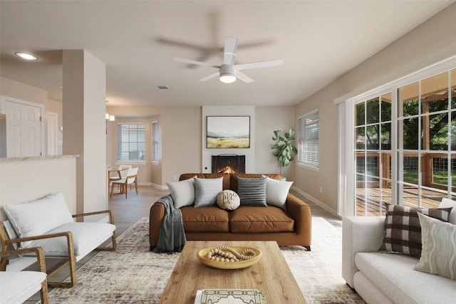 living area with a ceiling fan, baseboards, visible vents, wood finished floors, and a fireplace