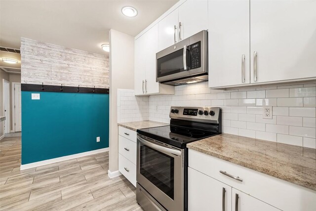 216 Lizzie St, Taylor, TX 76574 - kitchen with stainless steel appliances, white cabinets, light wood-type flooring, light stone countertops, and backsplash