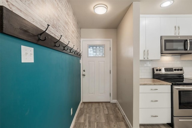216 Lizzie St, Taylor, TX 76574 - kitchen featuring stainless steel appliances, wood finished floors, backsplash, and white cabinets