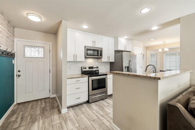 216 Lizzie St, Taylor, TX 76574 - kitchen with appliances with stainless steel finishes, decorative backsplash, white cabinets, light wood-style flooring, and plenty of natural light