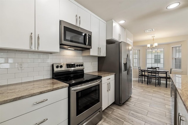 216 Lizzie St, Taylor, TX 76574 - kitchen featuring appliances with stainless steel finishes, a chandelier, white cabinets, decorative light fixtures, and decorative backsplash