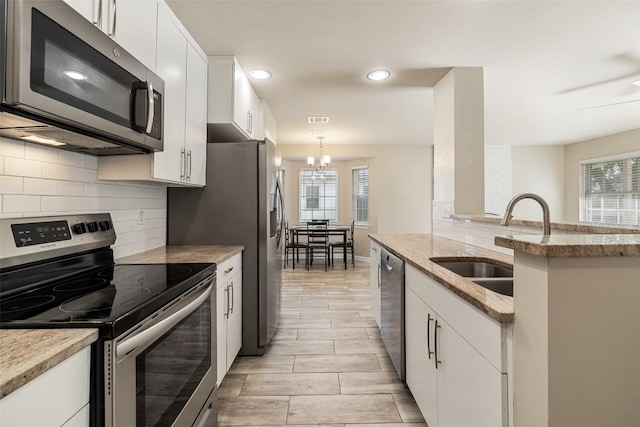 216 Lizzie St, Taylor, TX 76574 - kitchen with appliances with stainless steel finishes, white cabinetry, tasteful backsplash, a chandelier, and recessed lighting
