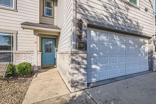 338 Liberty St, Hutto, TX 78634 - doorway to property featuring brick siding, driveway, and a garage