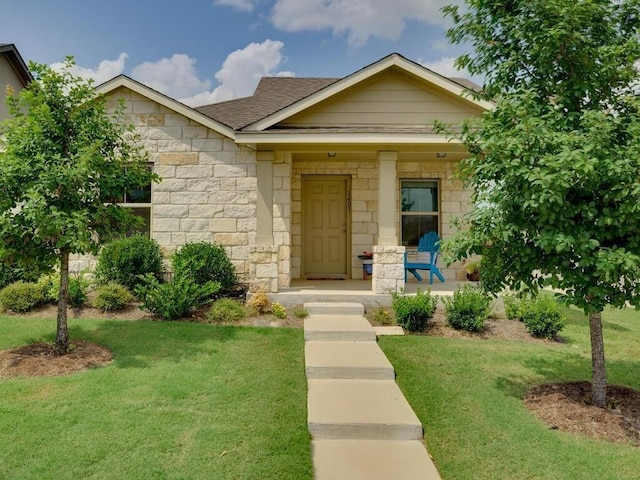 view of front of property featuring stone siding, a porch, roof with shingles, and a front yard