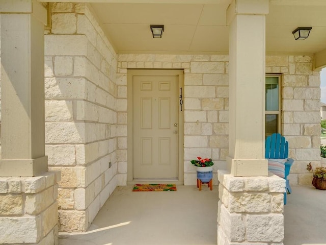 view of exterior entry with stone siding and covered porch
