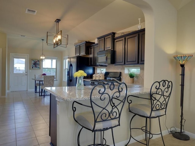 kitchen featuring light tile patterned flooring, black appliances, light stone counters, dark brown cabinetry, and baseboards
