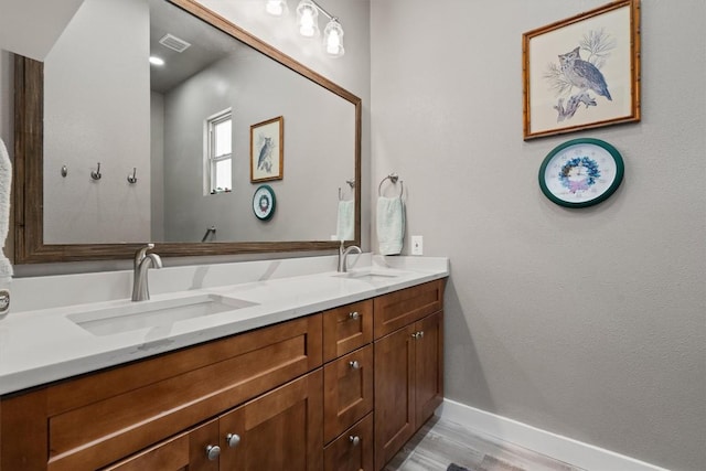bathroom featuring baseboards, visible vents, a sink, and double vanity