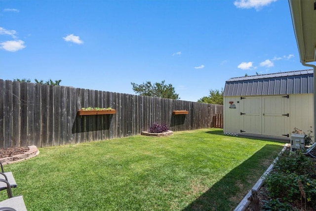 view of yard featuring a fenced backyard, a shed, and an outbuilding