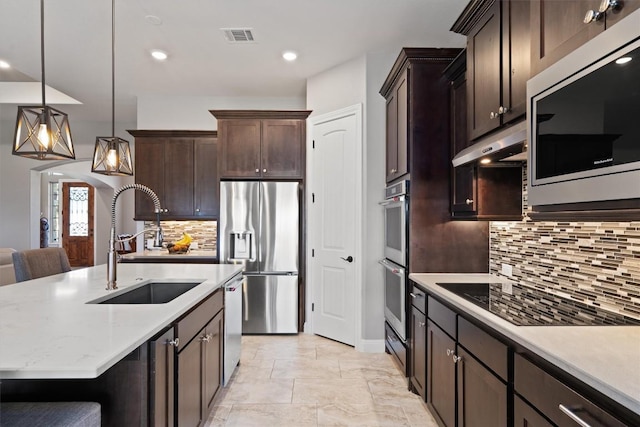 kitchen with a sink, stainless steel appliances, visible vents, under cabinet range hood, and dark brown cabinets