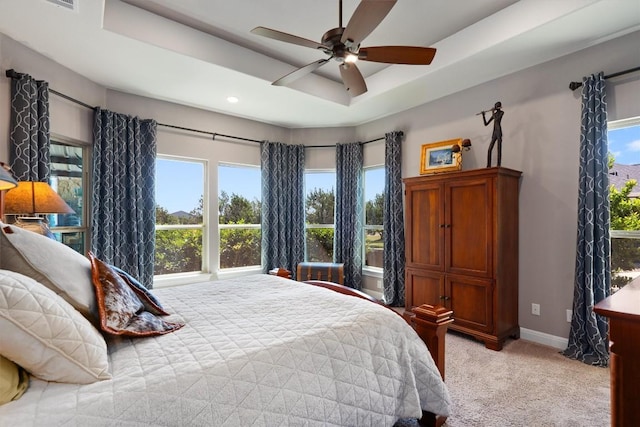 bedroom featuring multiple windows, light carpet, and a tray ceiling