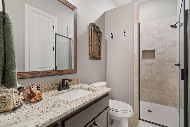 bathroom with a stall shower, vanity, toilet, and decorative backsplash