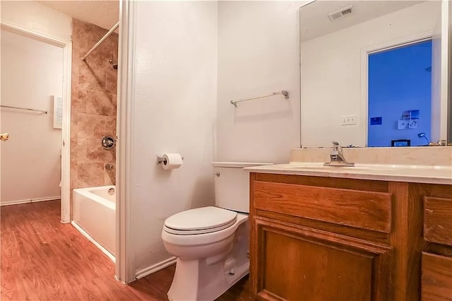 full bath with toilet, visible vents, vanity, shower / washtub combination, and wood finished floors