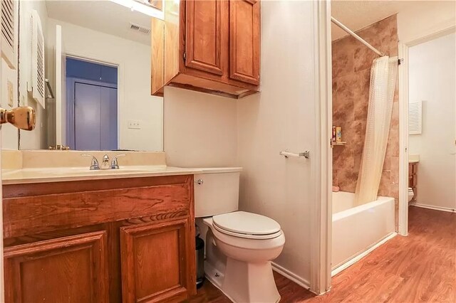 bathroom featuring toilet, wood finished floors, vanity, shower / tub combo with curtain, and visible vents