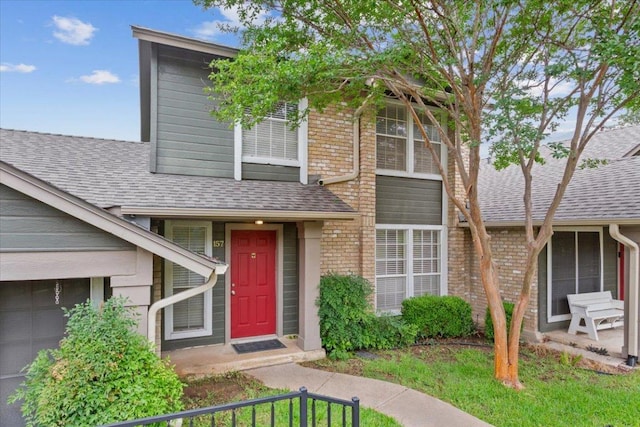 1015 E Yager Ln Unit 157, Austin, TX 78753 - view of front facade with roof with shingles, brick siding, and an attached garage