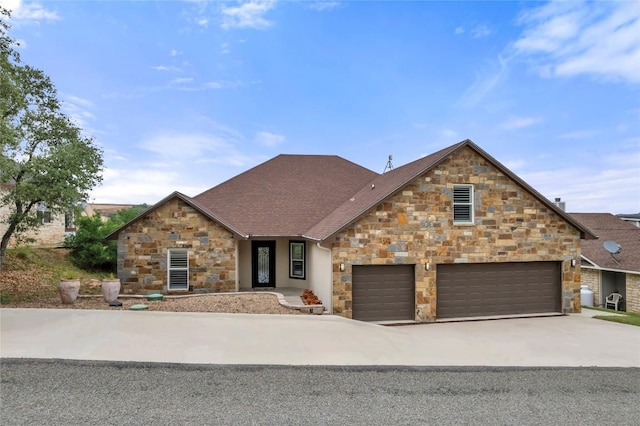 view of front facade featuring stone siding, concrete driveway, an attached garage, and a shingled roof