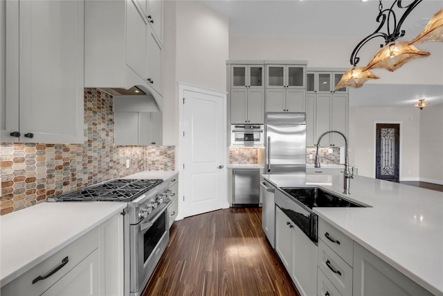 kitchen featuring hanging light fixtures, dark wood finished floors, a sink, high quality appliances, and light countertops