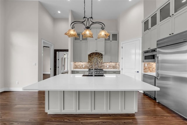 kitchen with a towering ceiling, light countertops, and built in fridge