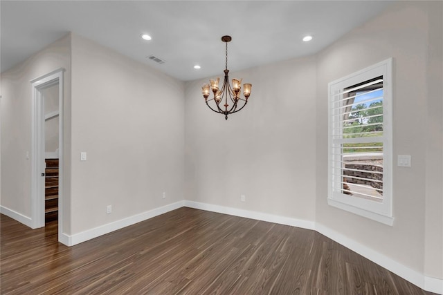 unfurnished room with baseboards, dark wood finished floors, a chandelier, and visible vents