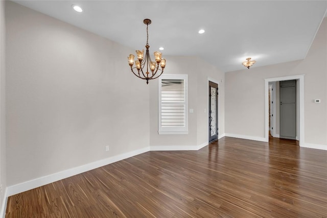 spare room featuring a chandelier, recessed lighting, baseboards, and dark wood finished floors