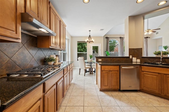 11121 Sandstone Trl, Austin, TX 78750 - kitchen featuring under cabinet range hood, appliances with stainless steel finishes, decorative backsplash, brown cabinets, and lofted ceiling