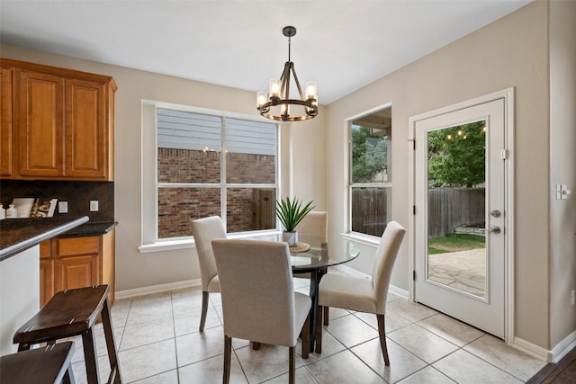 dining space featuring an inviting chandelier, light tile patterned flooring, and baseboards