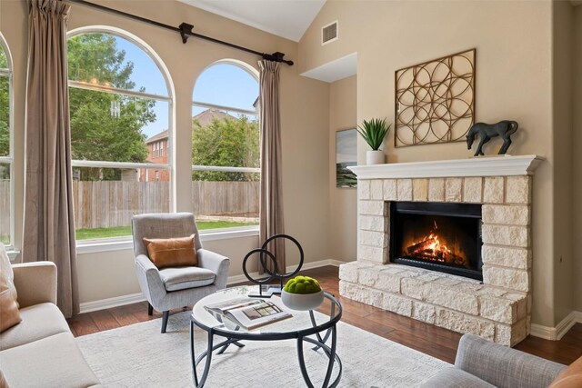 living room featuring plenty of natural light, visible vents, a fireplace, and lofted ceiling