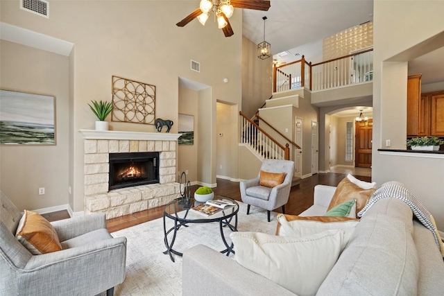 living area featuring a high ceiling, visible vents, ceiling fan, and stairs