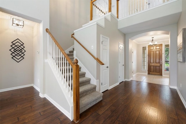 foyer with arched walkways, hardwood / wood-style floors, a high ceiling, and stairway