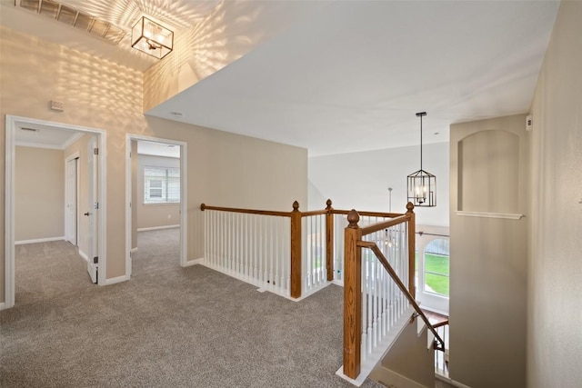 hallway featuring carpet, a chandelier, an upstairs landing, and baseboards