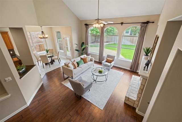 living area with hardwood / wood-style flooring, ceiling fan with notable chandelier, high vaulted ceiling, and baseboards