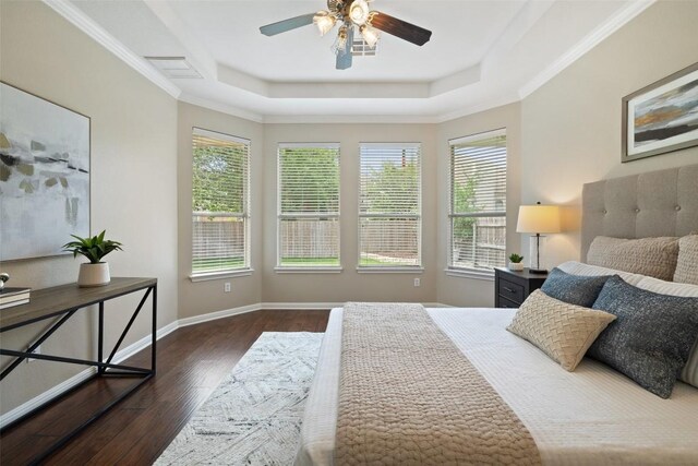 bedroom featuring a ceiling fan, a tray ceiling, baseboards, visible vents, and wood finished floors
