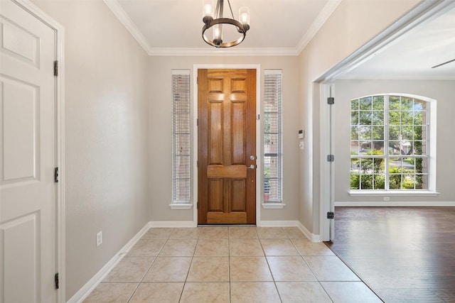 entrance foyer featuring light tile patterned floors, a chandelier, baseboards, and ornamental molding
