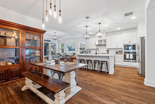 dining space with recessed lighting, a notable chandelier, visible vents, and wood finished floors