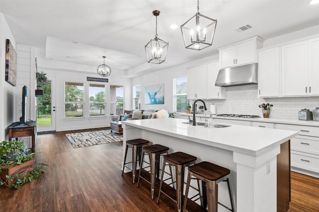 kitchen with an inviting chandelier, gas stovetop, a sink, under cabinet range hood, and light countertops