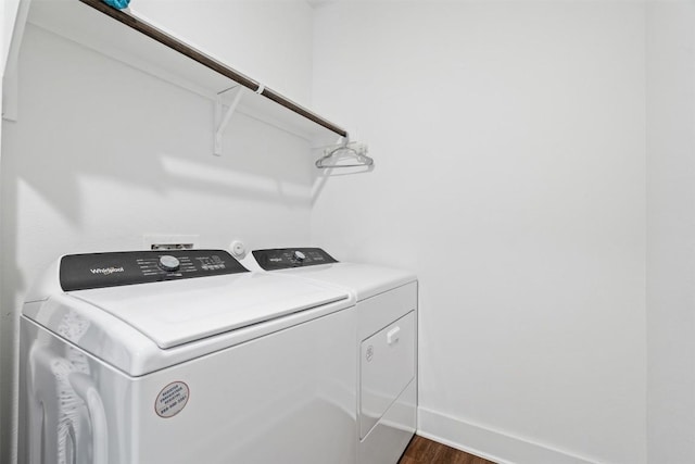 clothes washing area featuring baseboards, laundry area, washer and dryer, and dark wood-type flooring