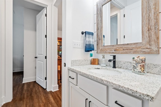 bathroom with baseboards, wood finished floors, and vanity