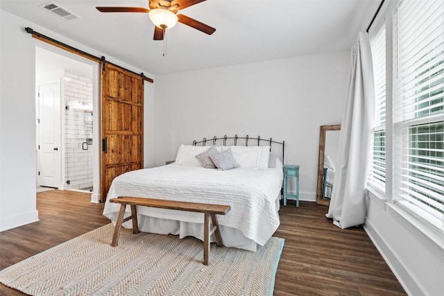 bedroom with dark wood finished floors, a barn door, visible vents, and multiple windows