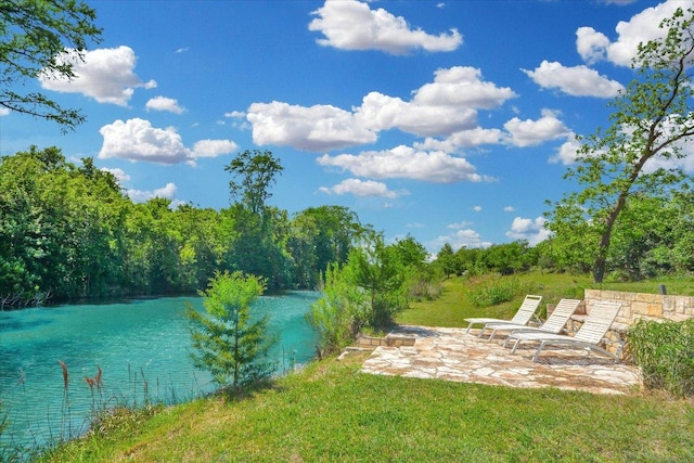 exterior space featuring a patio area, a water view, and a view of trees