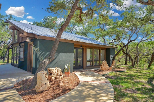 exterior space with stucco siding, french doors, and metal roof